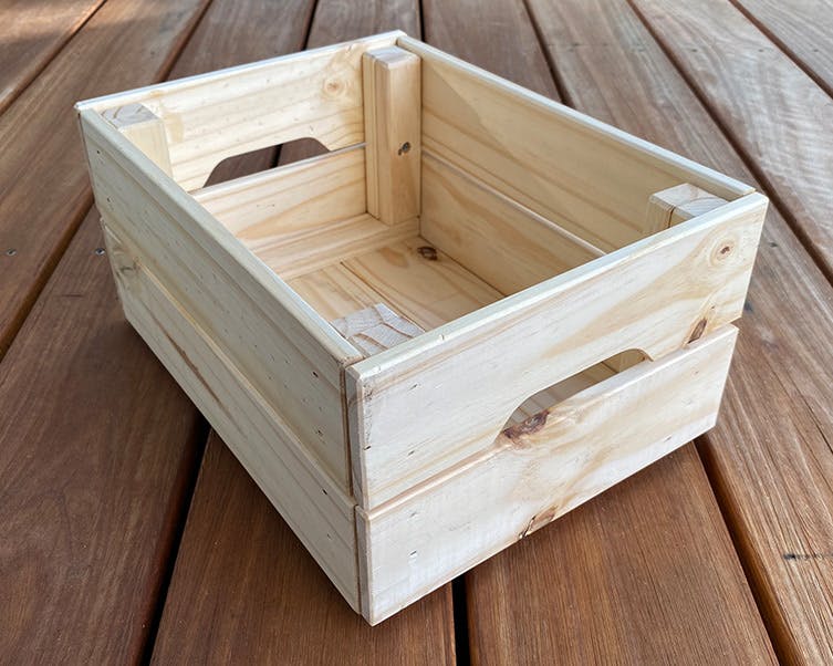 Sanding a wooden gift hamper crate with 120 grit sandpaper.