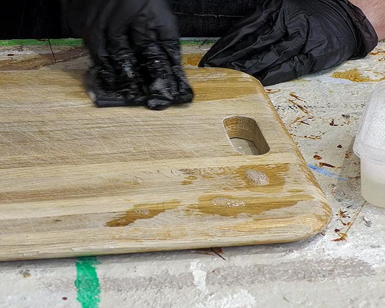 Wet sanding technique on a wooden chopping board.